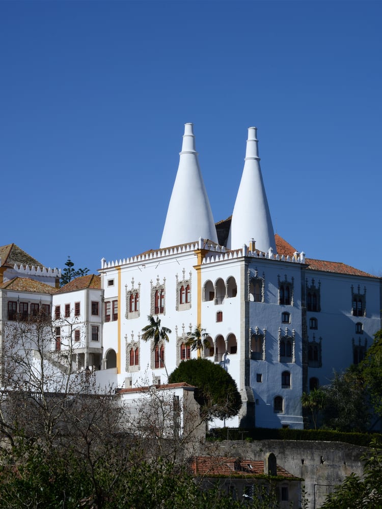 The Palácio Nacional de Sintra (Sintra National Palace) with its signature twin white conical kitchen chimneys rising above the old town of Sintra, Portugal. UNESCO World Heritage since 1995.